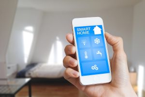 A person holding a smart phone for home automation inside a residence
